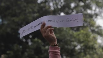 Pengungsi Afghanistan membawa kertas berisi pesan saat menggelar aksi unjuk rasa di depan Gedung UNHCR, Kebon Sirih, Jakarta, Selasa (24/8/2021). [Suara.com/Angga Budhiyanto]