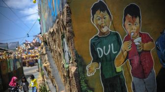 Sejumlah anak bermain di samping dinding yang dihiasi mural bertema keagamaan di Kampung Kukun Endah, Desa Cikoneng, Kabupaten Bandung, Jawa Barat, Kamis (26/1/2021).  ANTARA FOTO/Raisan Al Farisi