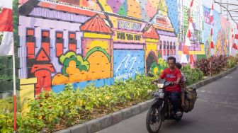 Sejumlah Warga Melintas di depan mural di Kampung Pink Tanah Tinggi Kota Tangerang Jumat 27 Agustus 2021 ( Suara.com/ Hilal Rauda Fiqry)