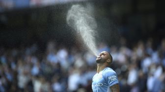 Bek Manchester City Kyle Walker menyemprotkan air menjelang pertandingan sepak bola Liga Premier Inggris antara Manchester City dan Arsenal di Stadion Etihad, Manchester, Inggris, pada (28/8/2021). [Oli SCARFF / AFP]