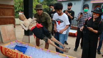 Sejumlah kerabat mengangkat jenazah keluarga untuk dibersihkan saat ritual Manene di Pangala, Kecamatan Rindingallo, Kabupaten Toraja Utara, Sulawesi Selatan, Jumat (27/8/2021). ANTARA FOTO / Sevianto Pakiding
