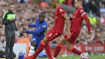 Gelandang Chelsea N'Golo Kante (kiri) mengoper bola melewati pemain tengah Liverpool Fabinho dan pemain tengah Liverpool Jordan Henderson (kanan) selama pertandingan sepak bola Liga Utama Inggris antara Liverpool dan Chelsea di Anfield, Liverpool, Inggris, pada (28/8/2021). [Paul ELLIS / AFP]