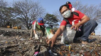 Warga memungut sampah di pinggir pantai kawasan Kedung Cowek, Surabaya, Jawa Timur, Minggu (29/8/2021). [ANTARA FOTO/Didik Suhartono]