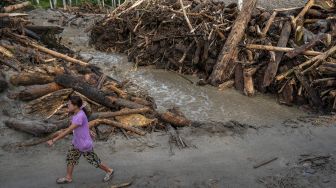 Sejumlah warga berada di antara tumpukan potongan kayu yang terbawa saat terjadi banjir bandang di Desa Rogo, Dolo Selatan, Sigi, Sulawesi Tengah, Senin (30/8/2021). [ANTARA FOTO/Basri Marzuki]