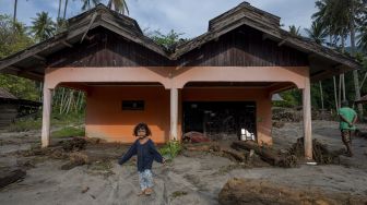 Seorang anak berjalan di depan rumahnya yang tertimbun lumpur akibat terjangan banjir bandang di Desa Rogo, Dolo Selatan, Sigi, Sulawesi Tengah, Senin (30/8/2021). [ANTARA FOTO/Basri Marzuki]