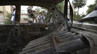 Pejuang Taliban menyelidiki mobil yang rusak setelah beberapa roket ditembakkan di Kabul, Afghanistan, Senin (30/8/2021). [Wakil Kohsar / AFP]