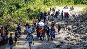 Warga memikul peti jenazah melintasi jalan Trans Palu-Kulawi yang sebagiannya tertimbun material longsoran di Desa Salua, Sigi, Sulawesi Tengah, Selasa (31/8/2021). ANTARA FOTO/Basri Marzuki