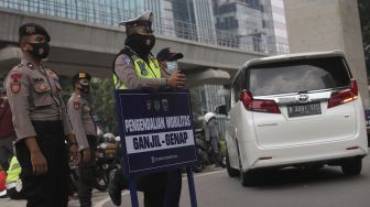 Polisi mengatur lalu lintas kendaraan di pos penerapan ganjil genap di Jalan HR Rasuna Said, Jakarta, Rabu (1/9/2021). [Suara.com/Angga Budhiyanto]