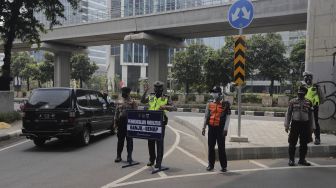 Polisi mengatur lalu lintas kendaraan di pos penerapan ganjil genap di Jalan HR Rasuna Said, Jakarta, Rabu (1/9/2021). [Suara.com/Angga Budhiyanto]