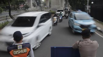 Polisi bersama petugas Dinas Perhubungan mengatur lalu lintas kendaraan di pos penerapan ganjil genap di Jalan HR Rasuna Said, Jakarta, Rabu (1/9/2021). [Suara.com/Angga Budhiyanto]
