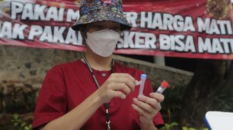 Petugas kesehatan menyiapkan wadah hasil sampel tes usap (swab test) antigen dan PCR gratis di Terowongan Kendal, Menteng, Jakarta, Kamis (2/9/2021). [Suara.com/Angga Budhiyanto]