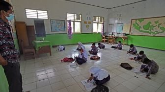 Guru mengajar sejumlah siswa yang duduk di lantai tanpa bangku dan meja belajar di SD Negeri Gelam 2 di Kampung Cigelam, Kecamatan Ciruas, Kabupaten Serang, Banten, Kamis (2/9/2021). ANTARA FOTO/Asep Fathulrahman
