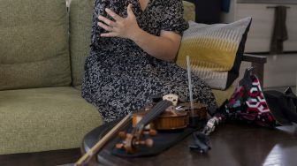 Biola dan lengan prostetik musisi Jepang Manami Ito terlihat saat dia berbicara selama wawancara di kediamannya di Shizuoka, Jepang, pada (28/8/2021). [Yuki IWAMURA / AFP]