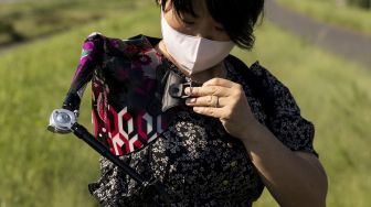 Musisi Jepang Manami Ito mengenakan lengan palsunya sebelum bermain biola selama sesi foto di Shizuoka, Jepang, pada (28/8/2021). [Yuki IWAMURA / AFP]