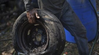 Seorang pekerja membawa ban saat memotong bangkai angkot di Depok, Jawa Barat, Minggu (5/9/2021). [ANTARA FOTO/Wahyu Putro A]