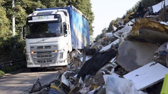 Sebuah truk melewati tumpukan sampah yang ditinggalkan di jalan raya A601 di Juprelle, Liege, Belgia, pada (3/9/2021). [François WALSCHAERTS / AFP] 