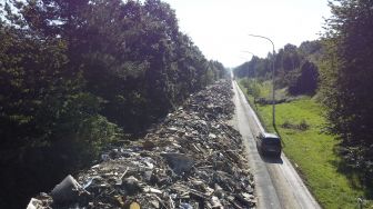 Foto udara menunjukkan tumpukan sampah yang ditinggalkan di jalan raya A601 di Juprelle, Liege, Belgia, pada (3/9/2021). [Kilian FICHOU / AFP] 