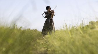 Musisi Jepang Manami Ito, yang juga seorang perawat berkualifikasi dan mantan perenang Paralimpiade, memainkan biola menggunakan lengan palsunya selama sesi foto di Shizuoka, Jepang, pada (28/8/2021). [Yuki IWAMURA / AFP]