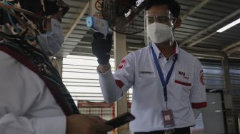 Petugas memeriksa suhu tubuh calon penumpang yang akan melakukan perjalanan menggunakan KAI Commuter Line di Stasiun Manggarai, Jakarta, Senin (6/9/2021). [Suara.com/Angga Budhiyanto]