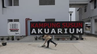 Warga berada di depan papan nama Kampung Susun Akuarium, Penjaringan, Jakarta, Senin (6/9/2021). [Suara.com/Angga Budhiyanto]