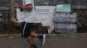 Pengunjung berlari di dekat tempat sampah dari botol bekas yang berada di kawasan Situ Gintung, Tangerang Selatan, Banten, Kamis (9/9/2021). [Suara.com/Angga Budhiyanto]