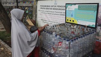 Pengunjung memasukkan sampah botol ke dalam tempat sampah yang berada di kawasan Situ Gintung, Tangerang Selatan, Banten, Kamis (9/9/2021). [Suara.com/Angga Budhiyanto]