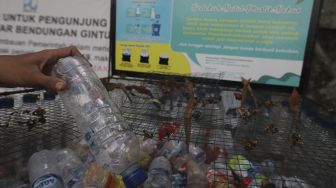 Pengunjung memasukkan sampah botol ke dalam tempat sampah yang berada di kawasan Situ Gintung, Tangerang Selatan, Banten, Kamis (9/9/2021). [Suara.com/Angga Budhiyanto]