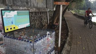 Pesepeda melintas di dekat tempat sampah dari botol bekas yang berada di kawasan Situ Gintung, Tangerang Selatan, Banten, Kamis (9/9/2021). [Suara.com/Angga Budhiyanto]
