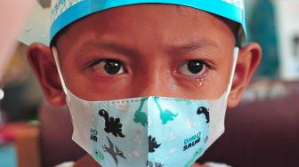 Seorang murid kelas 1 SD mendapatkan suntikan vaksin campak dari tenaga kesehatan di ruang kelas yang dihiasi ornamen pesta ulang tahun di SDN 28 Kota Jambi, Jambi, Kamis (9/9/2021).  ANTARA FOTO/Wahdi Septiawan

