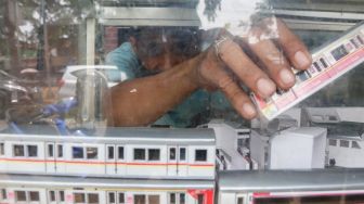 Iskandar (53) memajang hasil miniatur kereta api yang sudah selesai di kiosnya kawasan Manggarai, Jakarta Selatan, Sabtu (11/9/2021). [Suara.com/Alfian Winanto]