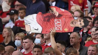 Seorang pendukung memegang replika striker Manchester United Cristiano Ronaldo selama pertandingan sepak bola Liga Premier Inggris antara Manchester United dan Newcastle di Old Trafford, Manchester, Inggris, Sabtu (11/9/2021). [Oli SCARFF / AFP]