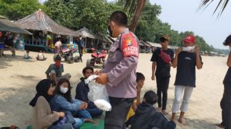 Cegah Penyebaran Covid-19, Polisi Bagikan Masker ke Wisatawan di Pantai Cinangka