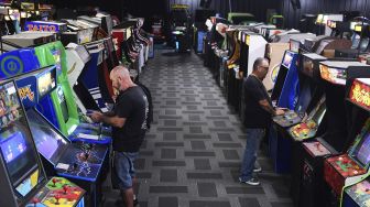 Karyawan rumah lelang bermain video game saat menguji mesin yang akan dilelang di Museum of Pinball di Banning, California, pada (10/9/2021). [Frederic J. BROWN / AFP]