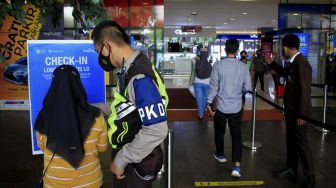 Petugas mendampingi pengunjung untuk memindai kode batang dari aplikasi PeduliLindungi sebelum memasuki Mall Tangerang City, Kota Tangerang, Banten, Senin (13/9/2021). [Suara.com/ Hilal Rauda Fiqry]