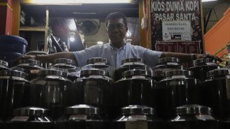 Pemilik Dunia Kopi, Suradi (42) berpose di kiosnya di Pasar Santa, Jakarta, Selasa (14/9/2021). [Suara.com/Angga Budhiyanto]