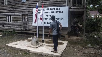 Wisatawan berdiri di atas patok perbatasan Indonesia-Malaysia di Pulau Sebatik, Senin (13/9/2021). ANTARA FOTO/Muhammad Adimaja