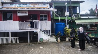 Wisatawan berfoto dengan latar belakang bendera Malaysia-Indonesia di Patok Perbatasan Indonesia-Malaysia, Pulau Sebatik, Senin (13/9/2021).  ANTARA FOTO/Muhammad Adimaja
