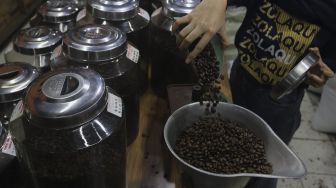 Pekerja menimbang biji kopi sebelum digiling di kios Dunia Kopi, Pasar Santa, Jakarta, Selasa (14/9/2021). [Suara.com/Angga Budhiyanto]