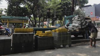 Pekerja menurunkan material proyek revitalisasi trotoar di Jalan Senopati, Kebayoran Baru, Jakarta, Rabu (15/9/2021). [Suara.com/Angga Budhiyanto]