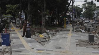 Warga berdiri di dekat proyek revitalisasi trotoar di Jalan Senopati, Kebayoran Baru, Jakarta, Rabu (15/9/2021). [Suara.com/Angga Budhiyanto]