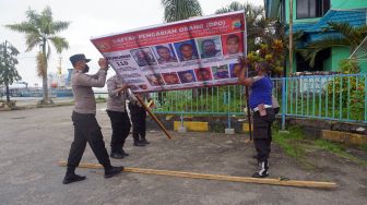 Polisi memasang baliho Daftar Pencarian Orang di Pelabuhan Laut Kota Sorong, Papua Barat, Kamis (16/9/2021). ANTARA FOTO/Olha Mulalinda