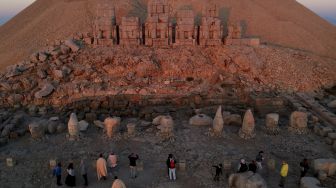 Foto udara menunjukkan wisatawan berada di situs arkeologi Gunung Nemrut di Adiyaman, Turki, Jumat (17/9/2021). [Yasin AKGUL / AFP]