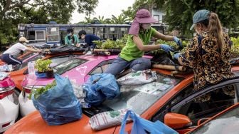 Petugas bengkel persewaan taksi menanam sayuran di atap salah satu kendaraan perusahaan yang tidak berfungsi karena penurunan bisnis akibat COVID-19 di Bangkok, Thailand, pada (15/9/2021). [Jack TAYLOR / AFP]