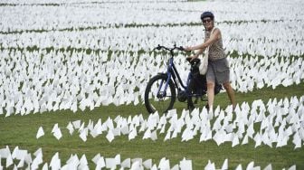 Warga mendorong sepedanya melewati bendera putih di dekat Monumen Washington, Washington, DC, pada (16/9/2021). [MANDEL NGAN / AFP]