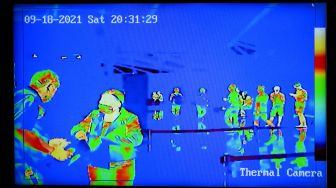 Petugas memeriksa dokumen perjalanan calon penumpang penerbangan repatriasi menuju Australia terlihat dari monitor "thermal camera" di area Terminal Internasional Bandara Internasional I Gusti Ngurah Rai, Badung, Bali, Sabtu (18/9/2021) malam. ANTARA FOTO/Fikri Yusuf
