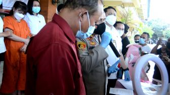 Petugas menghadirkan tersangka berinisial RR (kiri) dan menunjukkan barang bukti kasus pornografi saat konferensi pers di Polresta Denpasar, Bali, Senin (20/9/2021). ANTARA FOTO/Fikri Yusuf