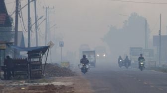 Sejumlah pengendara motor melintas di jalan yang diselimuti kabut asap kebakaran lahan di Kecamatan Liang Anggang, Banjarbaru, Kalimantan Selatan, Selasa (21/9/2021). ANTARA FOTO/Bayu Pratama S