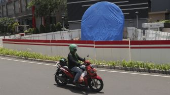 Pengendara sepeda motor melintas di dekat proyek pembangunan tugu sepeda di jalur pedestrian Jalan Jenderal Sudirman, Jakarta, Rabu (22/9/2021). [Suara.com/Angga Budhiyanto]