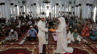 Pasangan pengantin menyerahkan mahar seusai melaksanakan prosesi ijab kabul di Masjid Raya Baiturrahman, Banda Aceh, Aceh, Kamis (23/9/2021). ANTARA FOTO/Syifa Yulinnas
