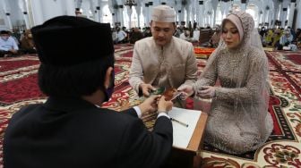 Pasangan pengantin mengambil buku nikah seusai melaksanakan prosesi ijab kabul di Masjid Raya Baiturrahman, Banda Aceh, Aceh, Kamis (23/9/2021). ANTARA FOTO/Syifa Yulinnas
